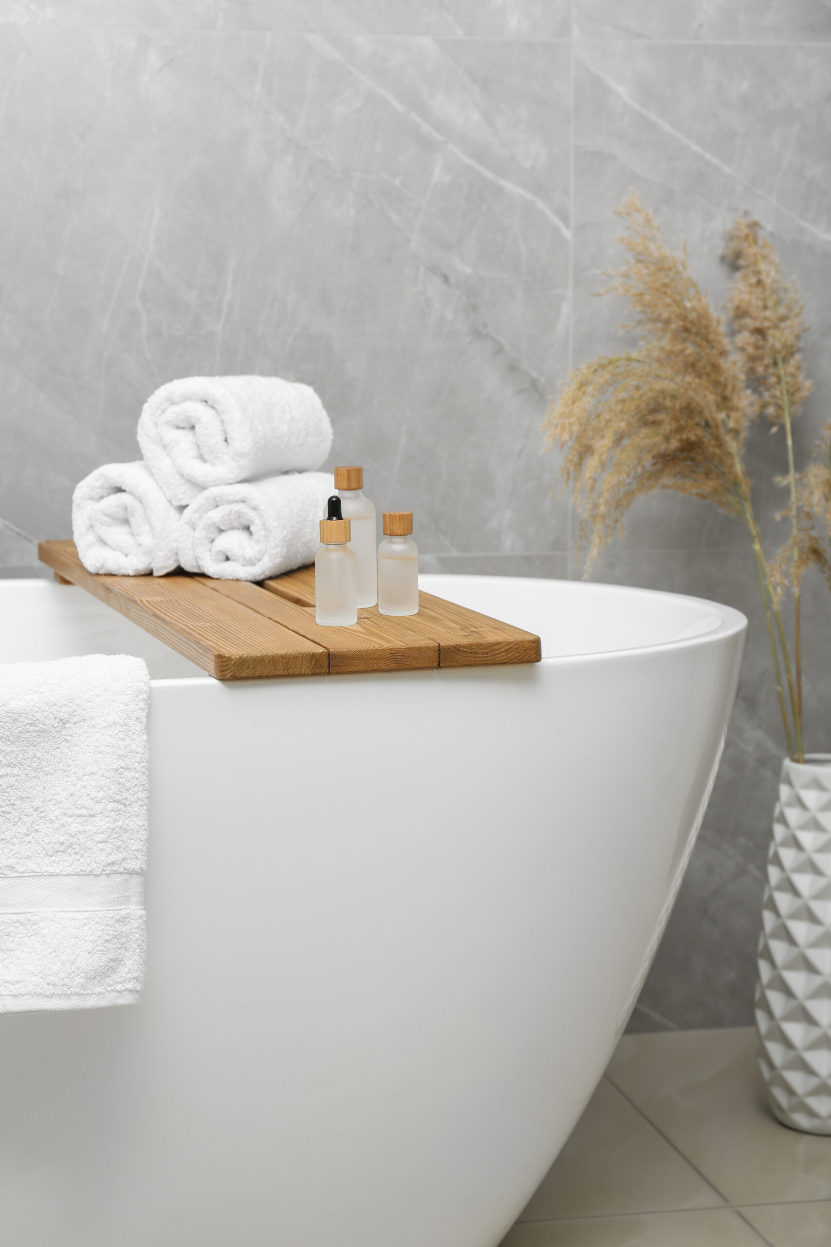 Rolled bath towels and personal care products on tub tray in bat